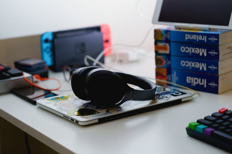 Casque bluetooth à réduction de bruit de Sony reposant sur un MacBook fermé sur un bureau debout dans un bureau à domicile.
