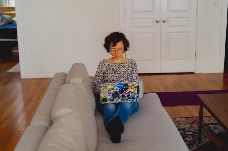Une femme assise sur un canapé avec un ordinateur portable.