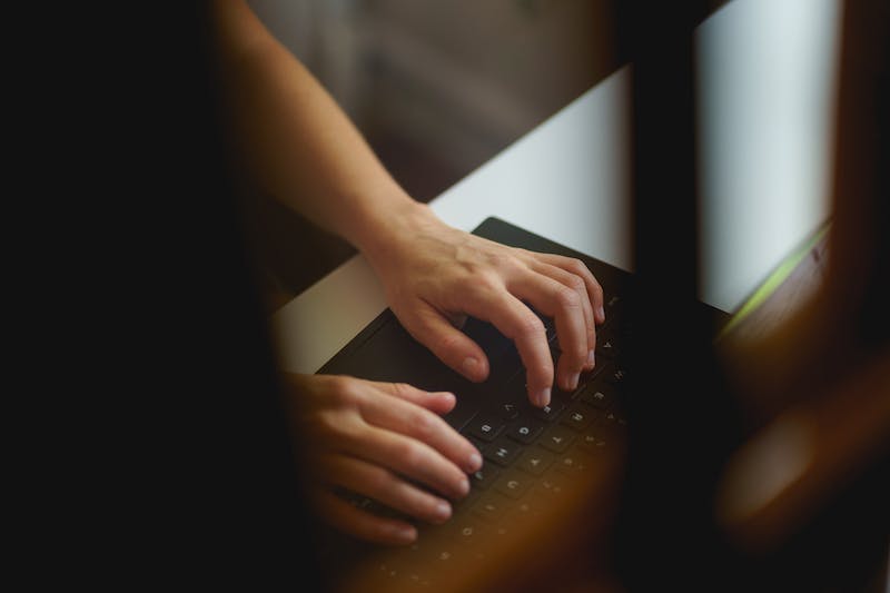 Femme tapant sur un clavier d'ordinateur portable noir de 13 pouces dans un petit bureau à domicile.