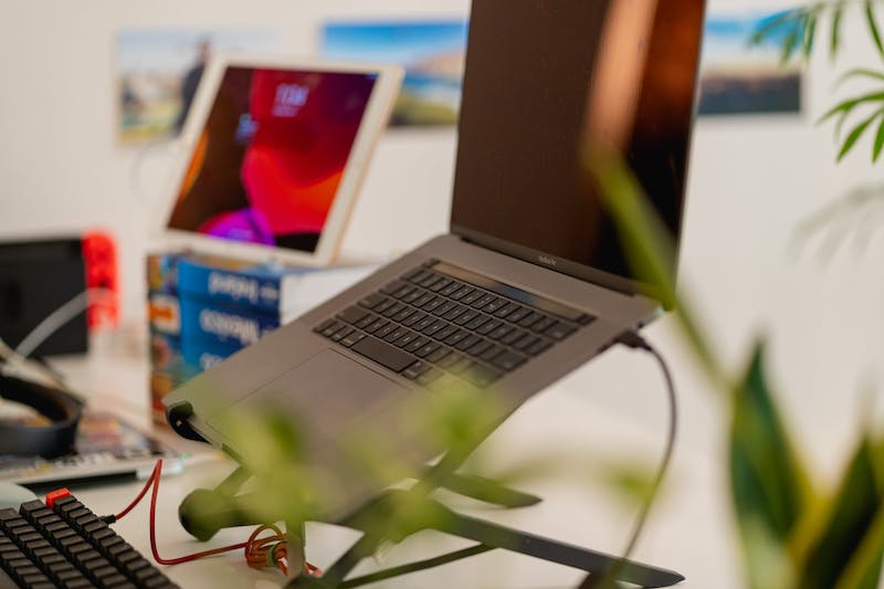 Utilisation d'un iPad comme moniteur externe sur une pile de livres à côté d'un ordinateur portable sur un support Roost pour ordinateur portable