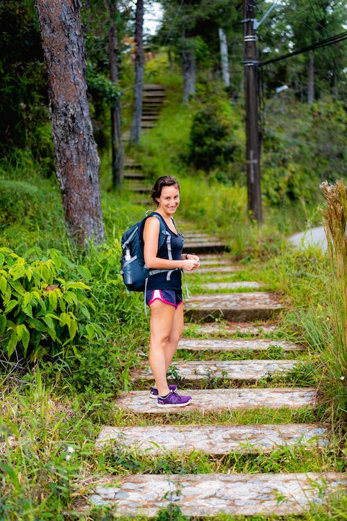 Femme portant un sac à dos et un short en train de monter des marches en pierre à Guatape en Colombie.