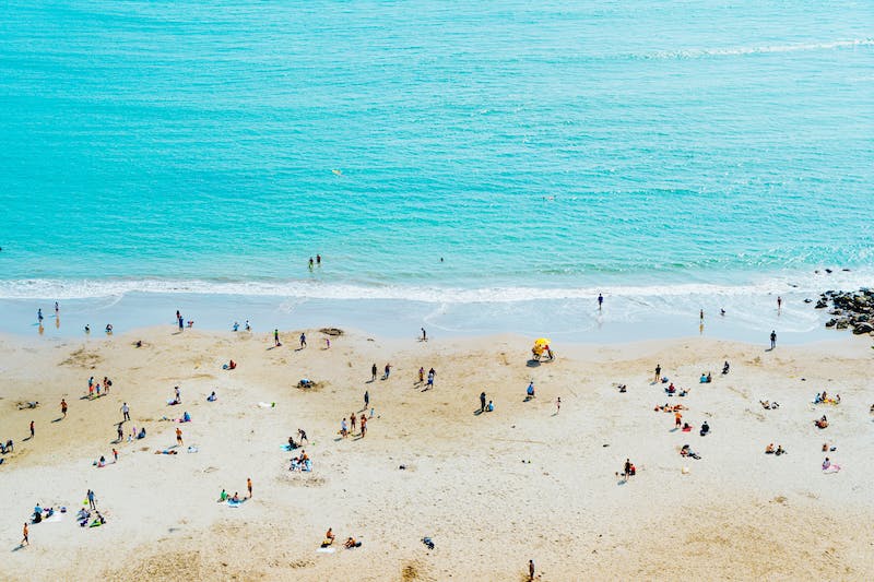 Plage de sable blanc à Lima, au Pérou, avec des baigneurs se dirigeant vers l'océan.