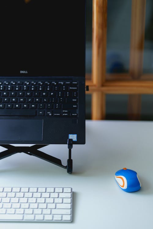 Mini souris externe logitech utilisée avec un ordinateur portable dans un support pour ordinateur portable et un clavier externe dans une installation de bureau à domicile.