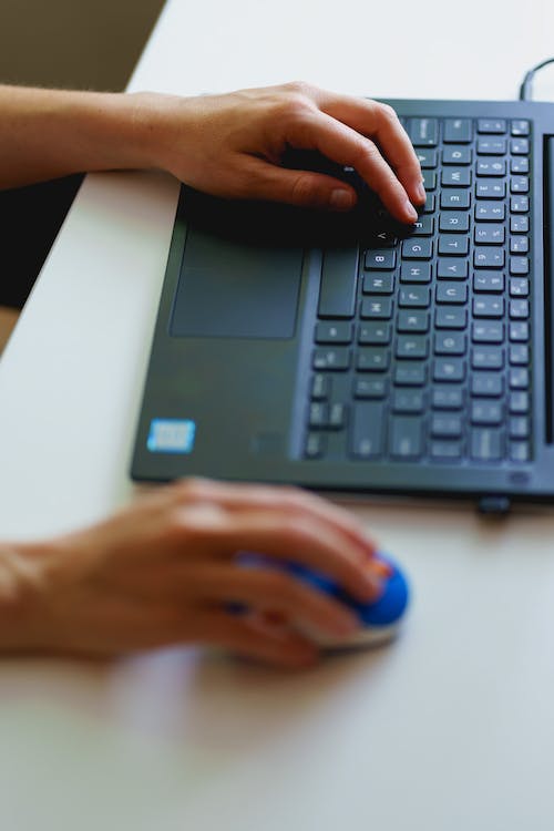 Dactylographie et travail à domicile avec un ordinateur portable sur un petit bureau blanc dans un bureau à domicile.