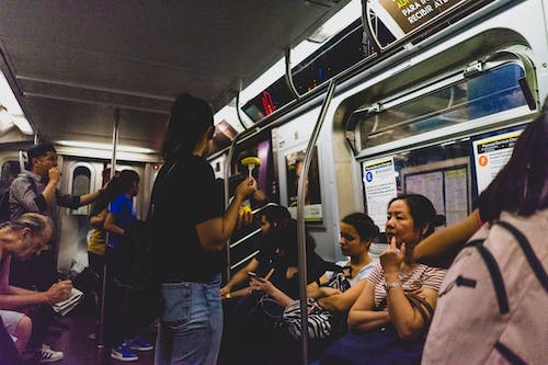 Intérieur d'une rame de métro de New York avec des passagers assis et debout à des poteaux pour s'accrocher.