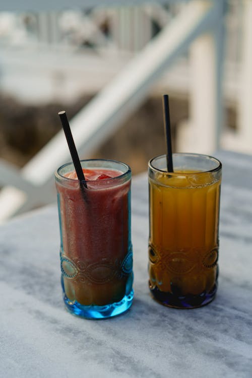Jus de fraises et de fruits de la passion dans des verres bleus sur un comptoir en quartz dans le patio d'un restaurant.