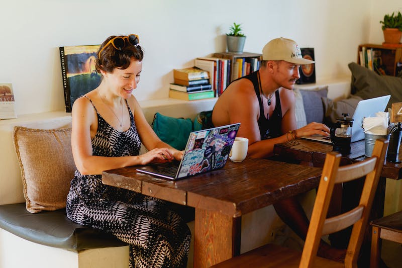 Femme travaillant à distance avec un ordinateur portable dans un café de plage branché