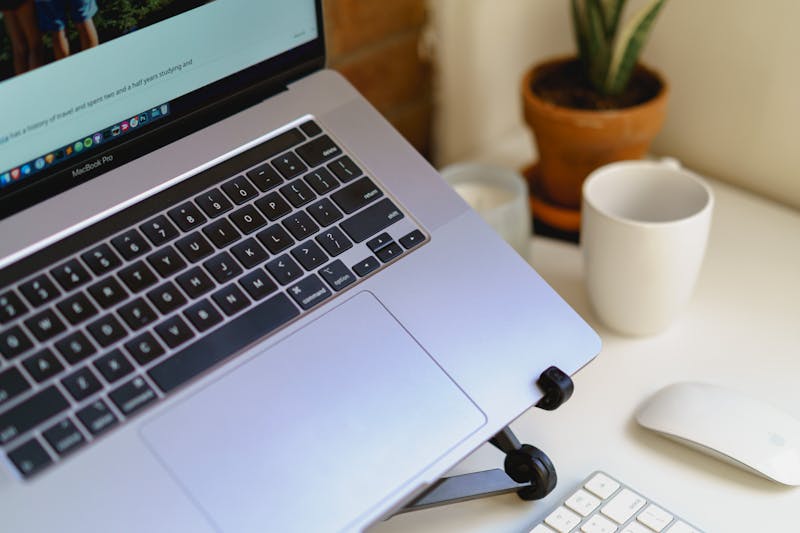 Gros plan sur un support noir pour ordinateur portable tenant un MacBook Pro argenté dans un petit appartement ou un bureau à domicile.