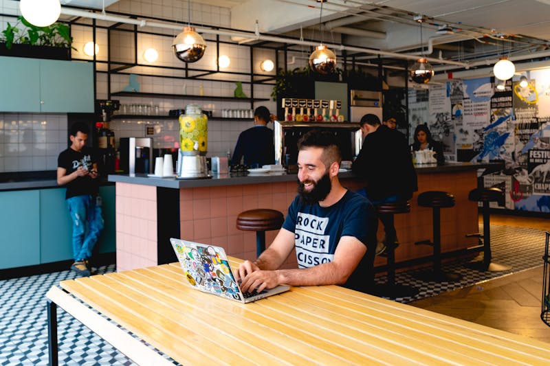 Homme travaillant sur son ordinateur portable dans un espace social de la cafétéria commune de WeWork.