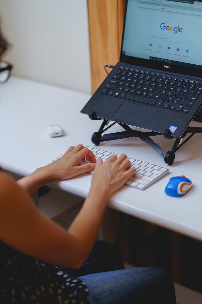 Dactylographie et travail à domicile sur un ordinateur portable avec un support d'ordinateur portable Roost et un clavier externe sur un petit bureau.