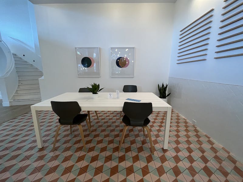 Une pièce avec une table et des chaises blanches et un escalier.
