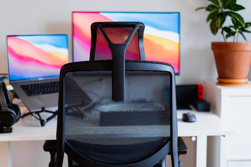 Une chaise de bureau avec un écran et un ordinateur portable.
