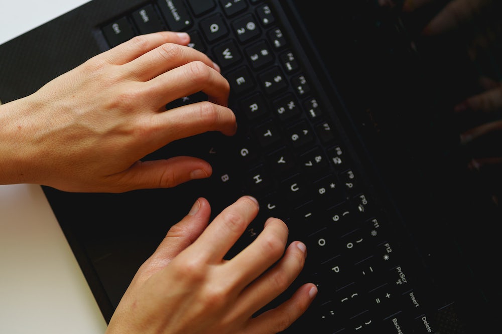 Femme tapant sur le clavier d'un ordinateur portable Dell XPS de petite taille alors qu'elle travaille depuis son domicile dans un bureau à domicile.