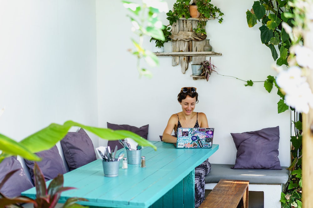 Femme utilisant un ordinateur Dell XPS sur une table d'équipe à l'extérieur dans un café