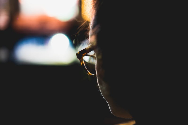 Bokeh de lumières derrière la silhouette d'une femme portant des lunettes